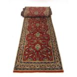 A Sarouk Persian runner with a red ground, blue floral centre and matching bands, 556 x 77 cm,