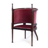 An Edwardian mahogany and upholstered 'enclosed' armchair with turned arms and tapering legs