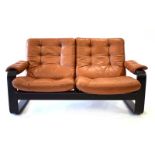 A Danish two-seater sofa with a black ash frame and brown leather button upholstery