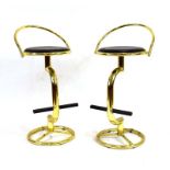 A pair of brass finished stools with black vinyl seats,