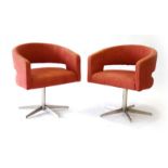 A pair of contemporary Swedish swivel chairs upholstered in pale red cotton on metal five-star