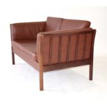 A Danish brown leather two seater sofa with an exposed beech frame