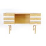 A 1960/70's oak desk, the surface with bevelled edges over six drawers with aluminium front panels,