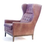 A 1970's brown button upholstered wingback armchair on stained tapering legs CONDITION