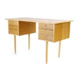 A 1970's oak desk, the rectangular surface over six drawers on tapering beech legs,