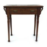 A Commercial Arts & Crafts oak writing table with a tooled leather surface over a frieze drawer,