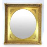 A 20th century oval mirror within a rectangular gilt border,