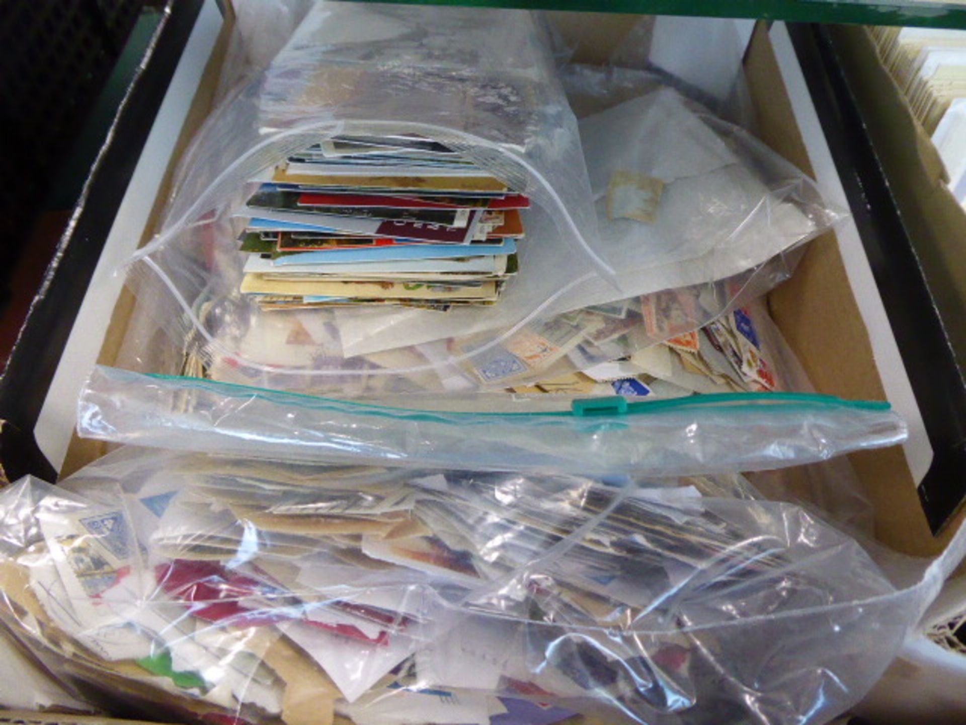 A cardboard tray containing a quantity of loose stamps in various packets