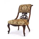 A Victorian mahogany and upholstered chair with a carved back on cabriole front legs with castors