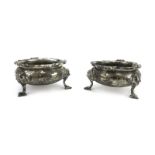 A pair of Victorian silver and parcel gilt salts of squat bun form, each on three scrolled feet,