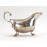 An Edwardian silver sauce boat with leaf capped handle on three foliate feet, Walker & Hall,