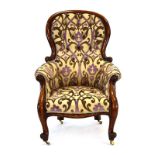 A Victorian mahogany and floral upholstered button back armchair with scrolled arms and front legs