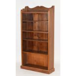 A 20th century pine open-fronted adjustable bookshelf with a scrolled top and plinth base, w.