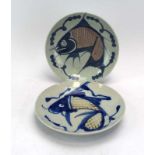 Two Chinese stoneware side plates, each decorated with a stylised fish, stamped marks to bases, d.