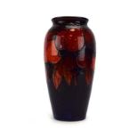 A Moorcroft vase of slender baluster form decorated with plums on a deep purple ground,