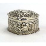 A metalwares hinged box of heart shaped form, repousse decorated with c-scrolls and foliate motifs,