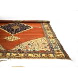 An early 20th century rug, the red ground with a large central medallion,