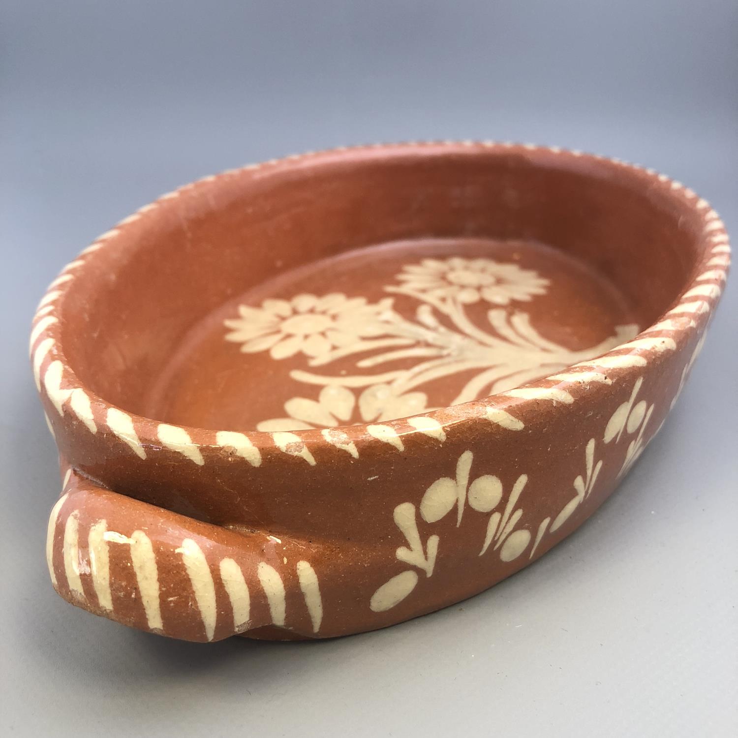 A twin handled slipware pottery dish of oval form with floral decoration - Image 5 of 5