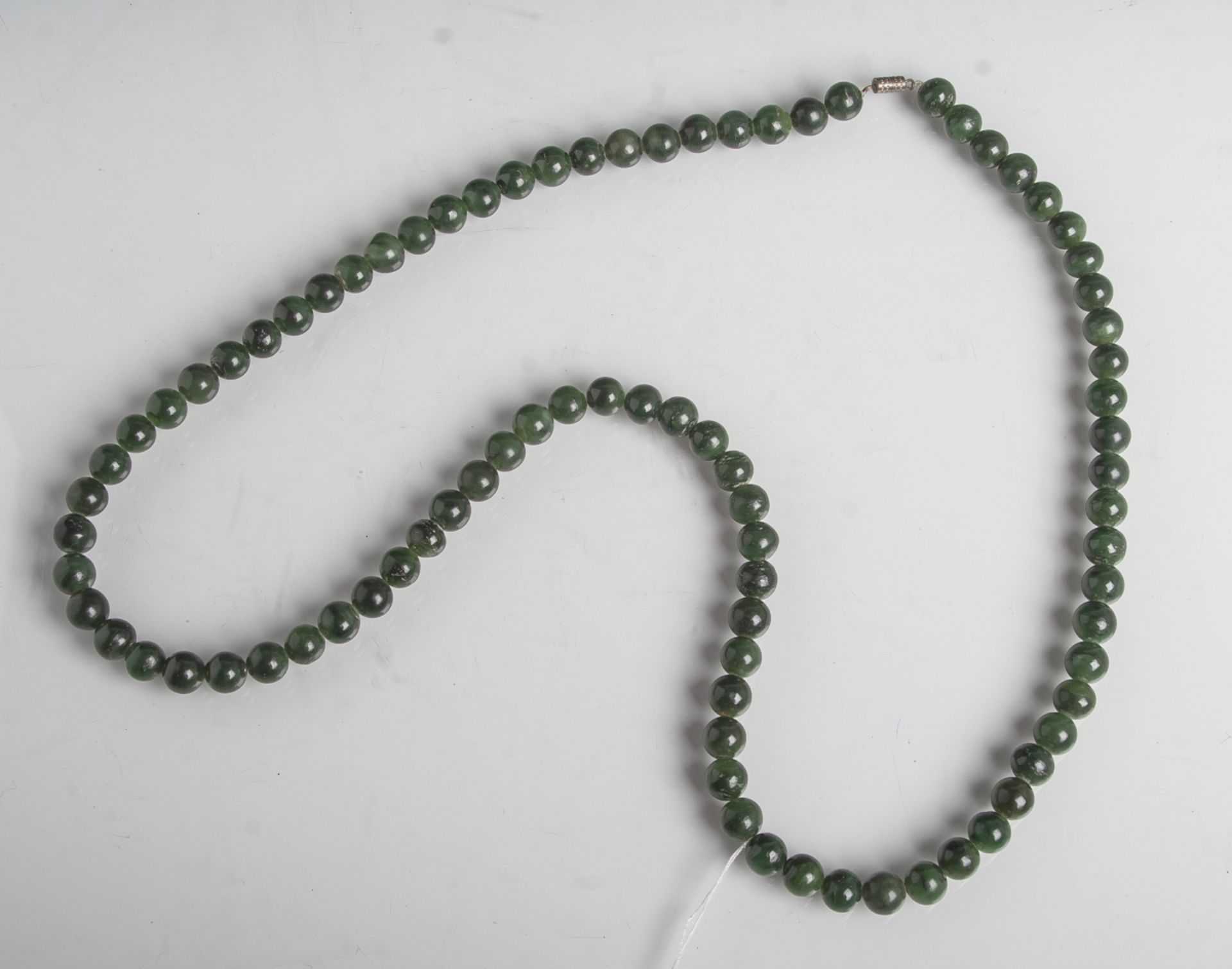 Halskette aus dunkelgrünen Jadekugeln mit Verschluss, L. ca 40 cm. Tragespuren.- - -21.00 % buyer'