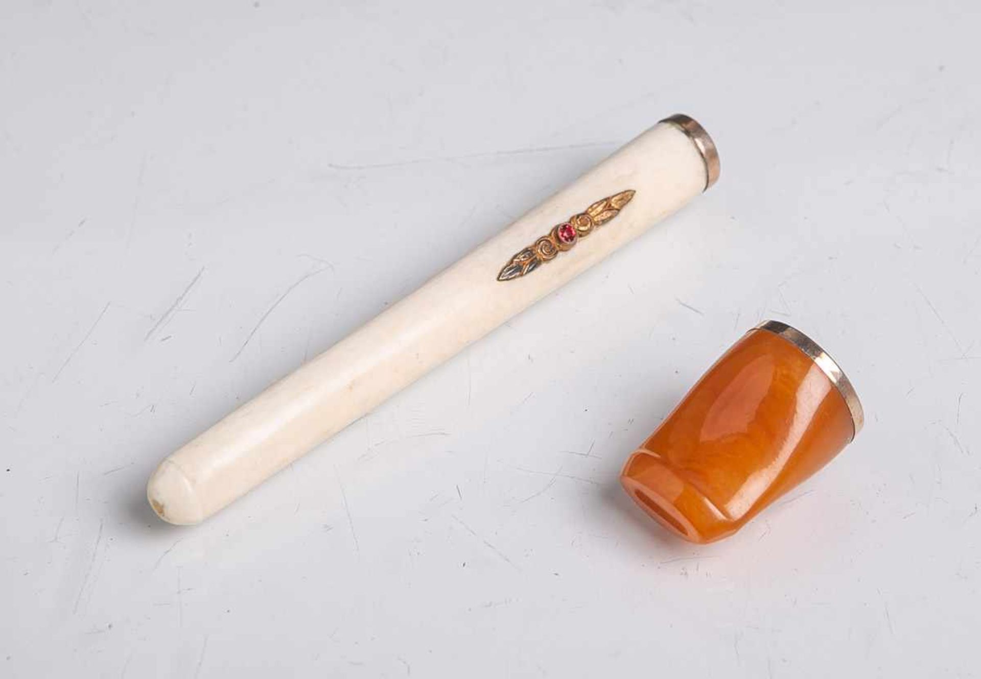 2 Zigarettenspitzen, davon 1x aus Bein, m. 2 roten Farbsteinen verziert, L. ca. 9 cm u. 1xwohl aus
