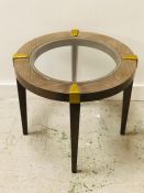 A contemporary circular side table with glass top