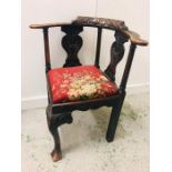 An Oak carved corner armchair with scroll detailing to back.