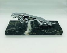 A Jaguar car mascot mounted on a marble plinth.