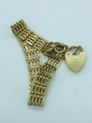 A 9ct yellow gold gate bracelet with heart shaped fastener and a safety chain, (15.1g)