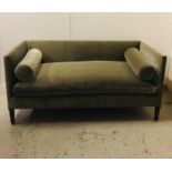 A Large sage green velvet sofa with bolster cushions.