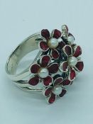 A silver ruby and pearl dress ring in the shape of a flower