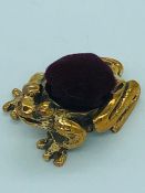 A brass pincushion in the form of a frog