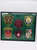 A set of six framed US Fire Fighters patches for various services.