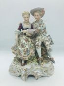 A Hand painted figure of a woman and a man seated.