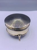 A sliver lidded circular jewellery box on tripod support