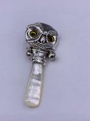 A silver babies rattle in the form of an owl with glass eyes with M O P handle