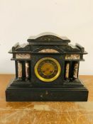 A Black slate mantle clock with pillared design.