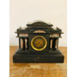 A Black slate mantle clock with pillared design.
