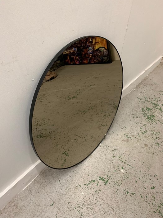 Circular mirror with thin black metal frame.