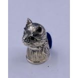 A silver cat pincushion with emerald eyes