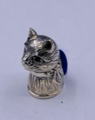 A silver cat pincushion with emerald eyes