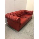 A Two seater Chesterfield sofa in a burnt orange colour.