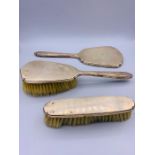 A silver dressing table set with two brushes and one mirror.
