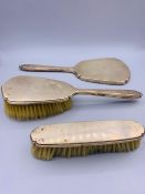 A silver dressing table set with two brushes and one mirror.