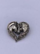 A silver brooch/pendant in the form of two horses with ruby eyes