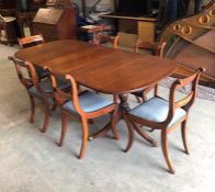 A Double pedestal dining table with centre leaf and six chairs with blue seat pads.