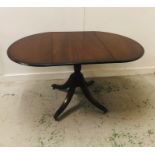 An Oval Drop Leaf Mahogany Dining Table on a Pedestal Base with Four Brass Claw Feet on Castors