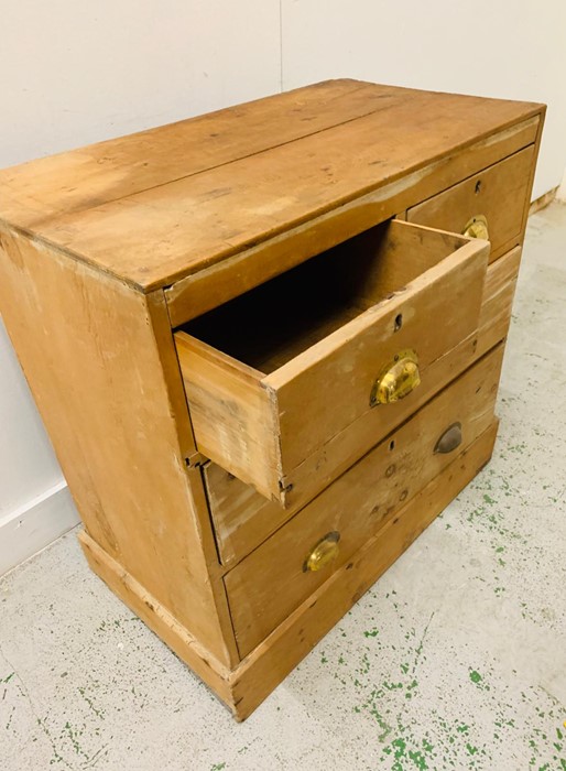 A Two over two pine chest of drawers with brass cup handles.