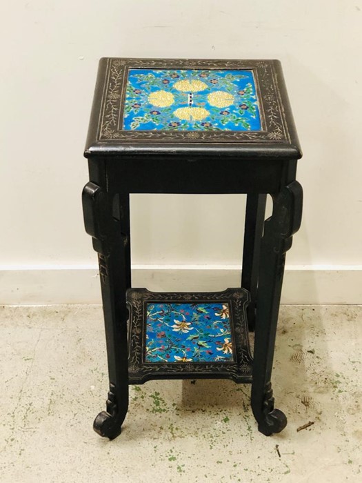 An ebonised pot stand with tiled top and lower shelf.