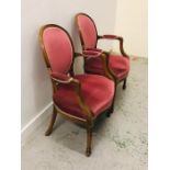 A Pair of large open armchairs with carved front legs in a pale crimson upholstery