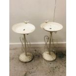 A Pair of White Metal Bird Baths with a Bird on The Rim